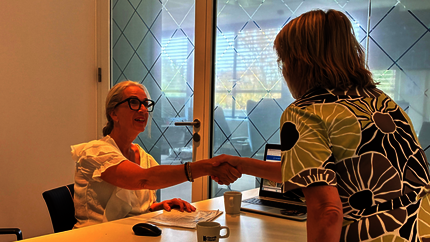 Een klantadviseur schut een huurder de hand om haar welkom te heten.